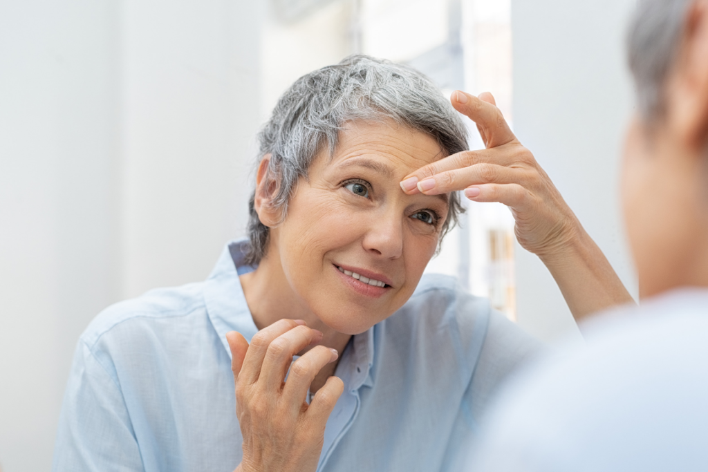 Mature woman looking at her wrinkles in a mirror