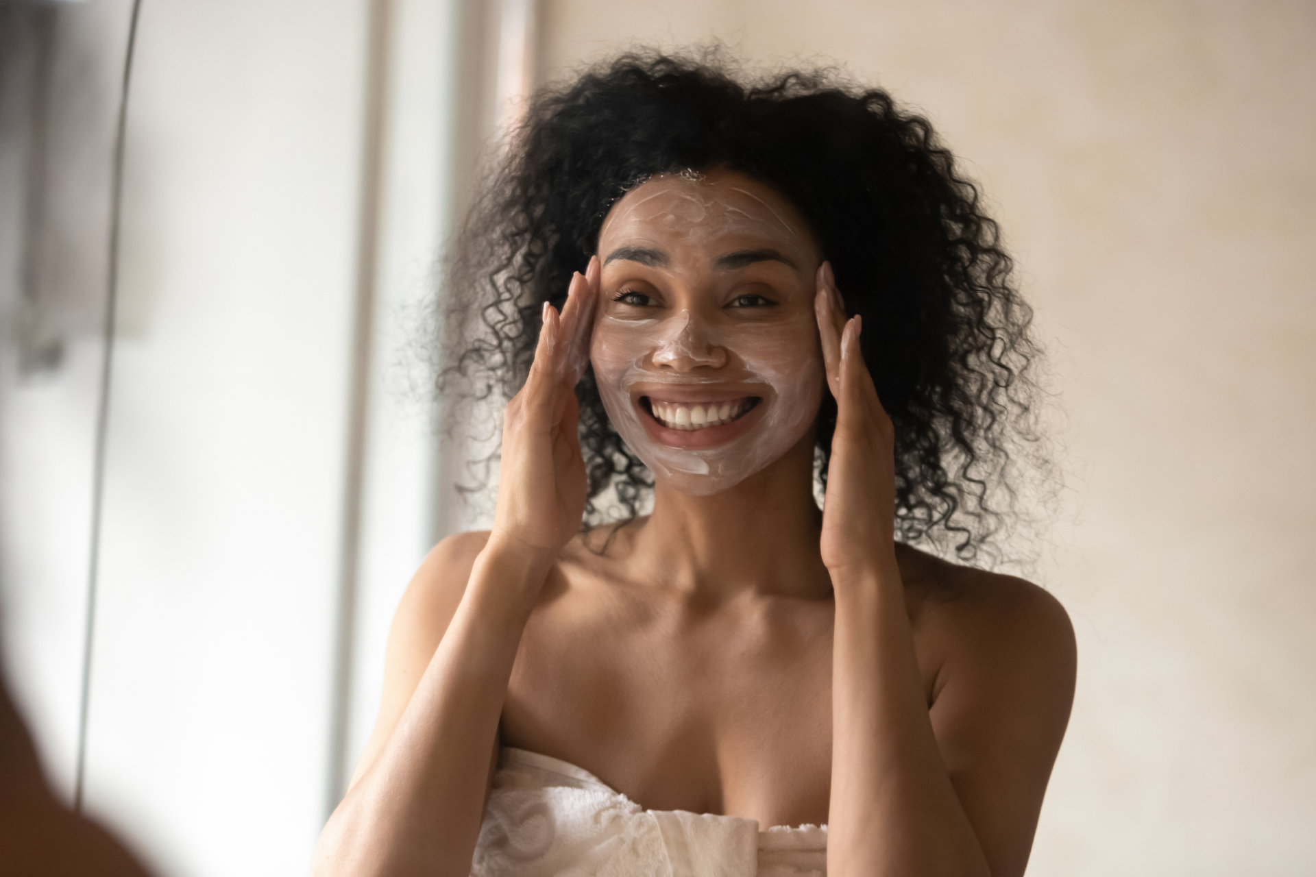 a woman smiling in the mirror after applying a chemical peel 