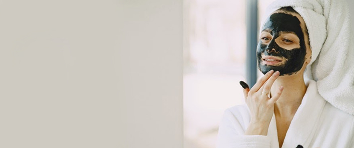 Photo of a woman applying black-colored skincare mask