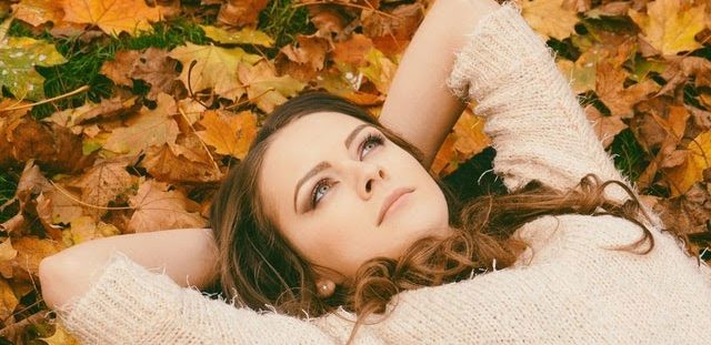 Woman lying down on the ground with autumn leaves