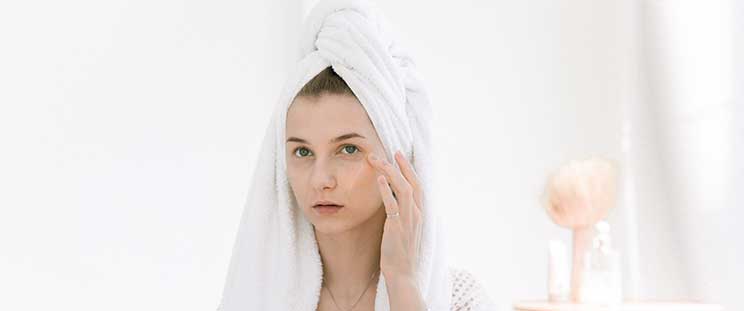 Woman applying skincare product on her face.
