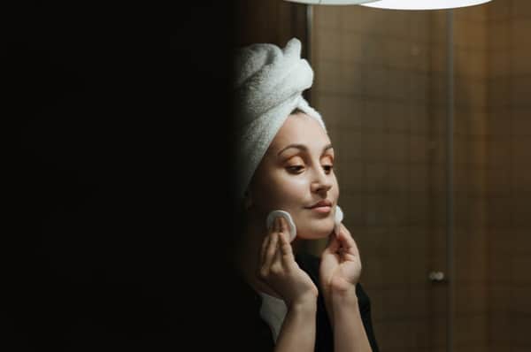 Woman removing makeup from her face with cotton pads