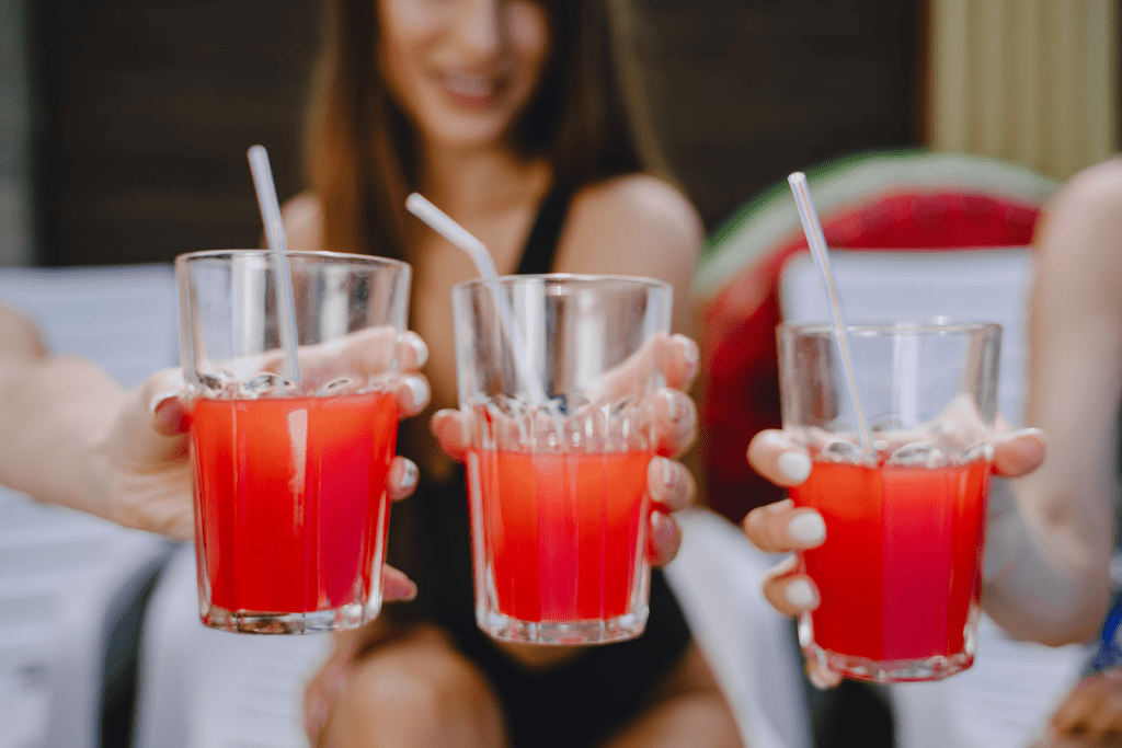 Three women cheers their mocktails towards the camera