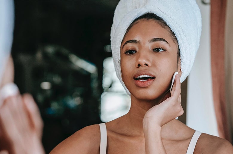 A woman wiping her face with cleansing pads