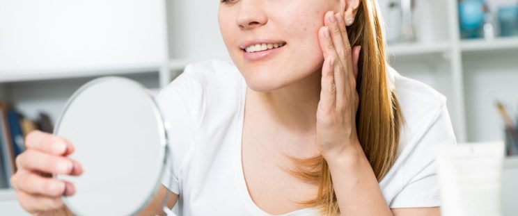 A woman looking at her skin in a mirror