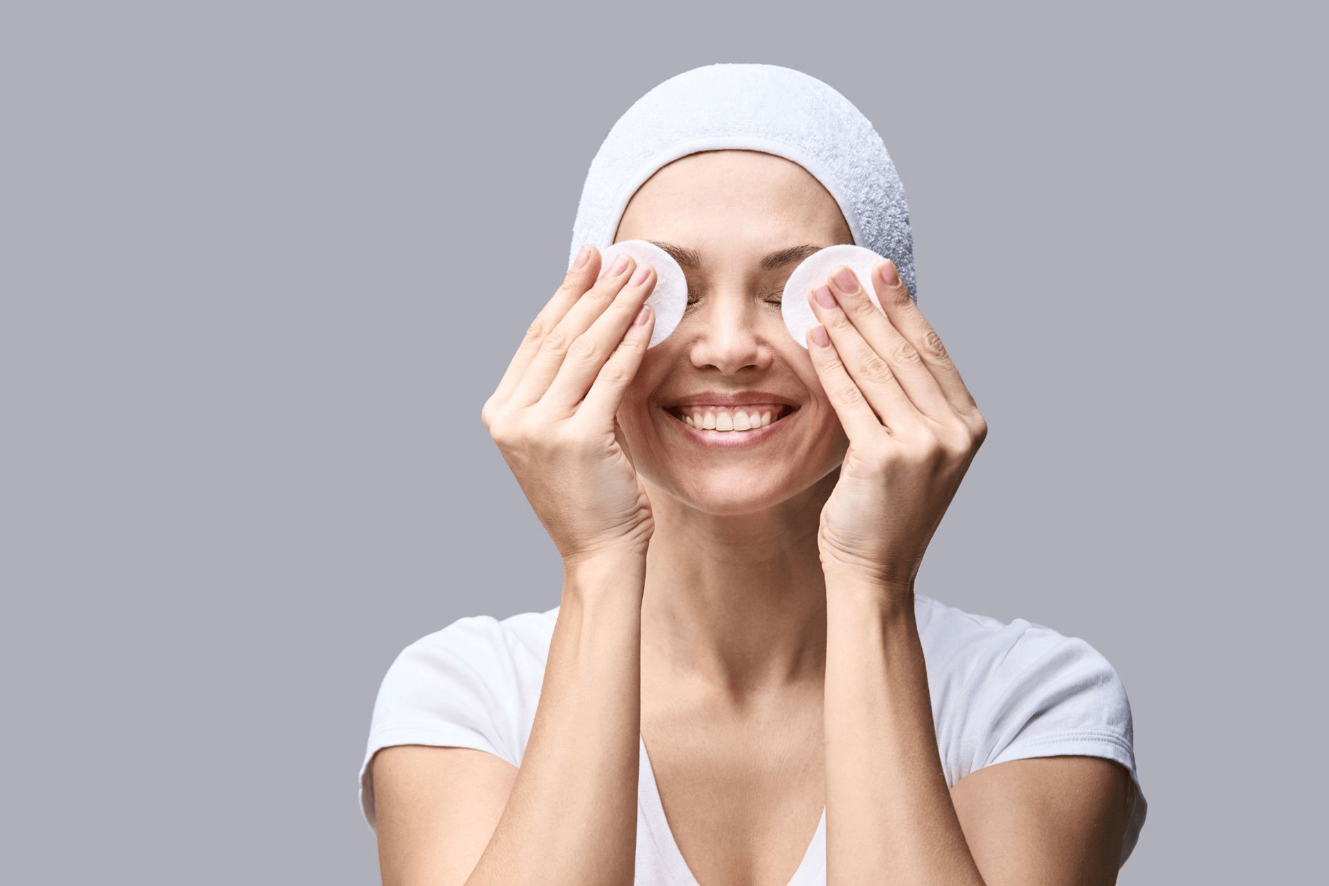 A woman applying toner to her face using circular cotton pads 