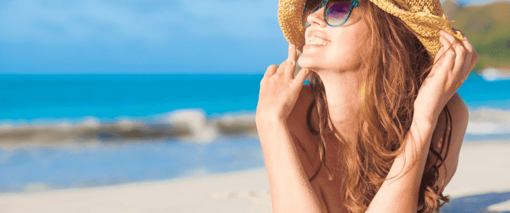 A smiling woman on the beach, under the sun