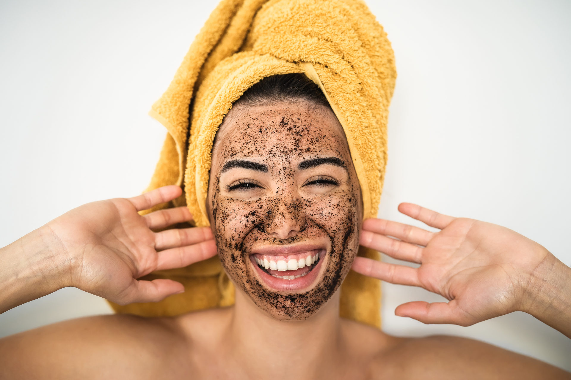 a woman exfoliating her face with a charcoal treatment
