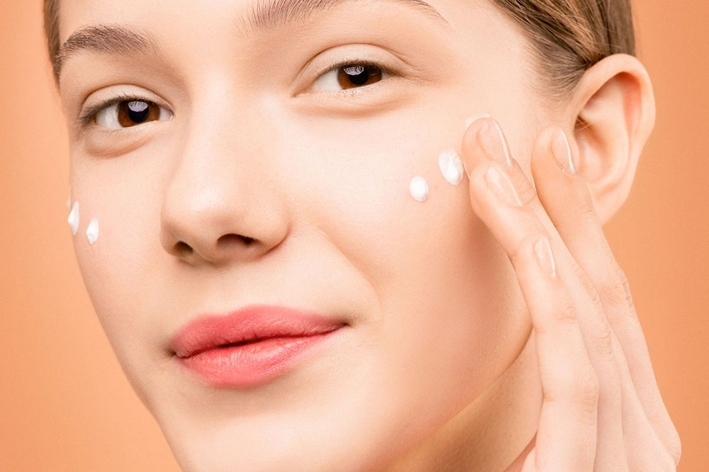 A woman applying beauty products on her face
