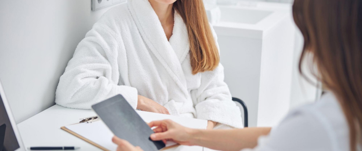 An aesthetician explains the treatment to a patient during skin consultation