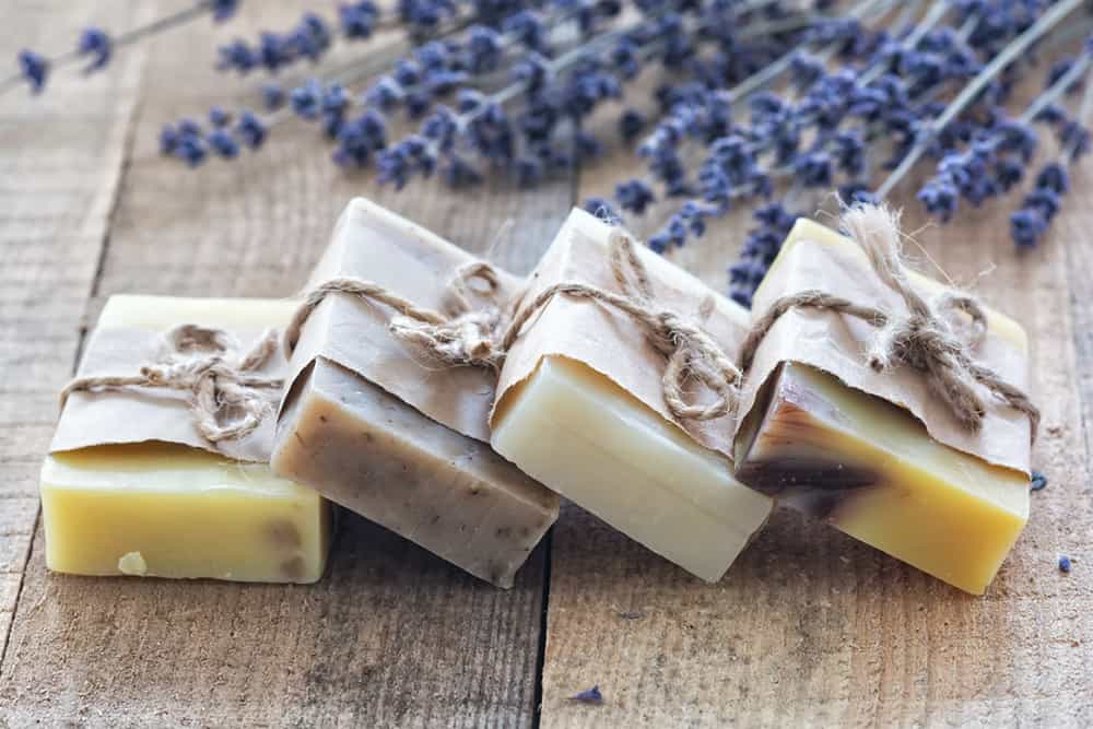 Four natural beauty bars in eco-friendly packaging with lavender in the background