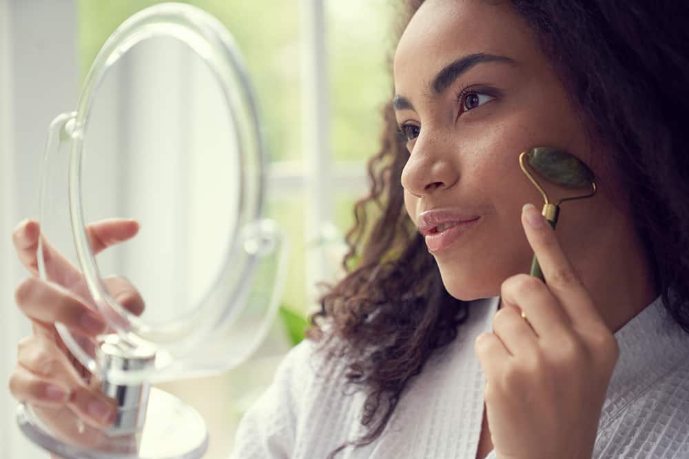 A woman uses a jade roller at home