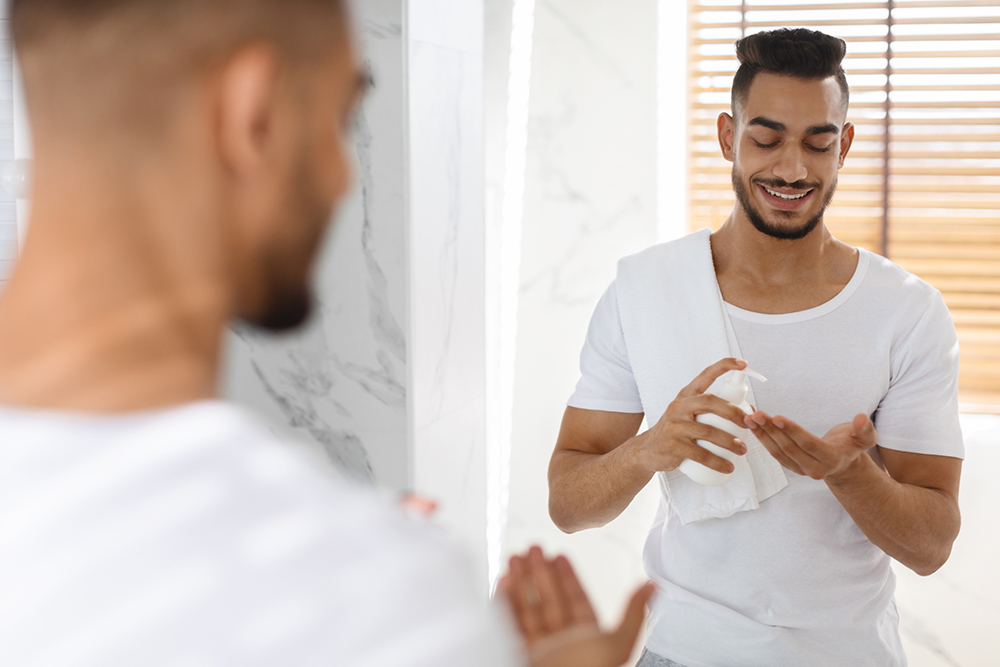  A man applies moisturizer to the palm of his hand