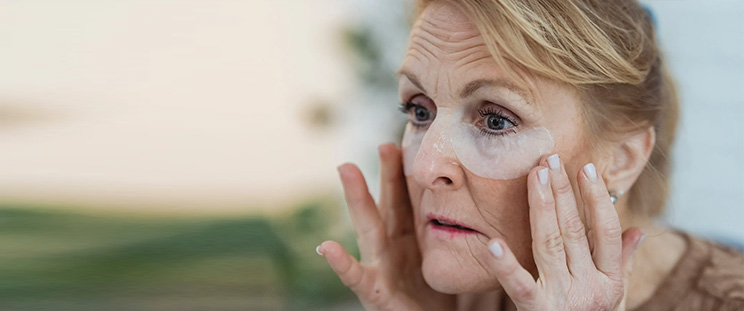 An older woman using under-eye patches