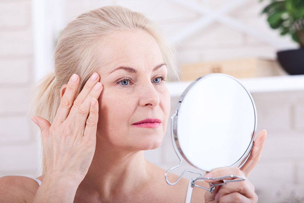 a woman looking at her skin in a mirror