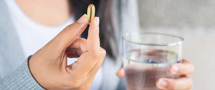 A woman holding an usana supplement and a glass of water