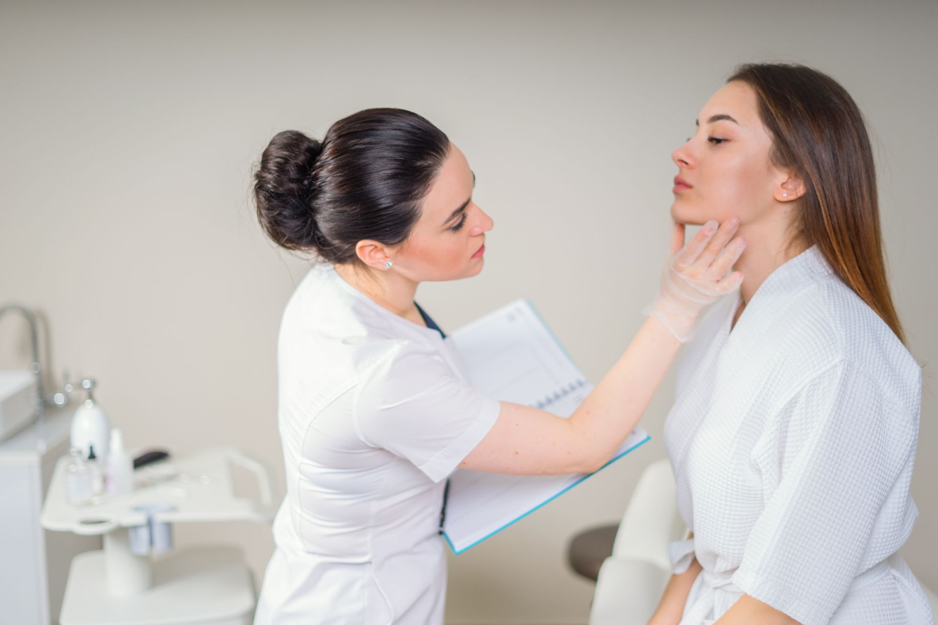A medical aesthetician checking a patient’s face for skin laxity