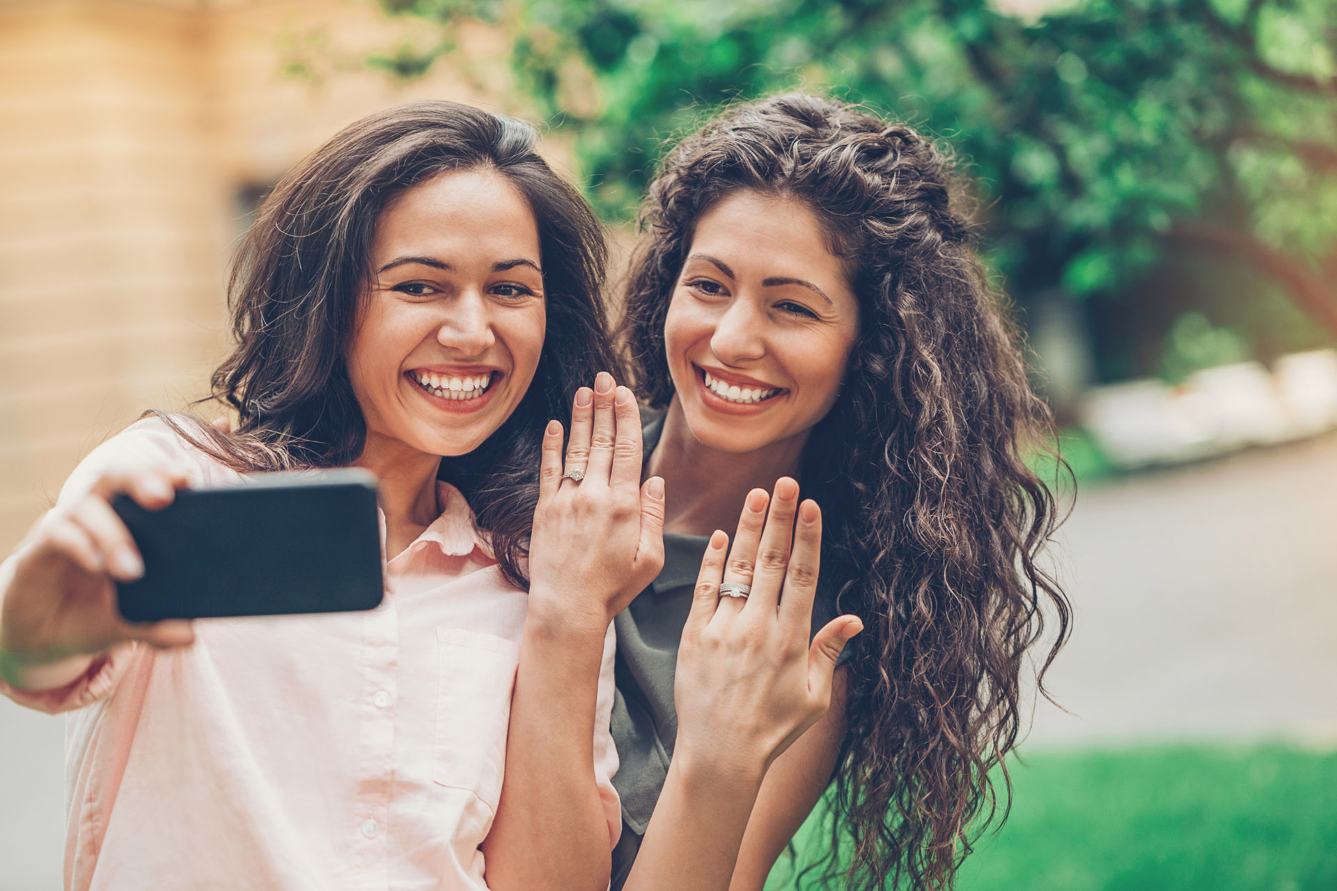 two women newly engaged showing off their rings over video call
