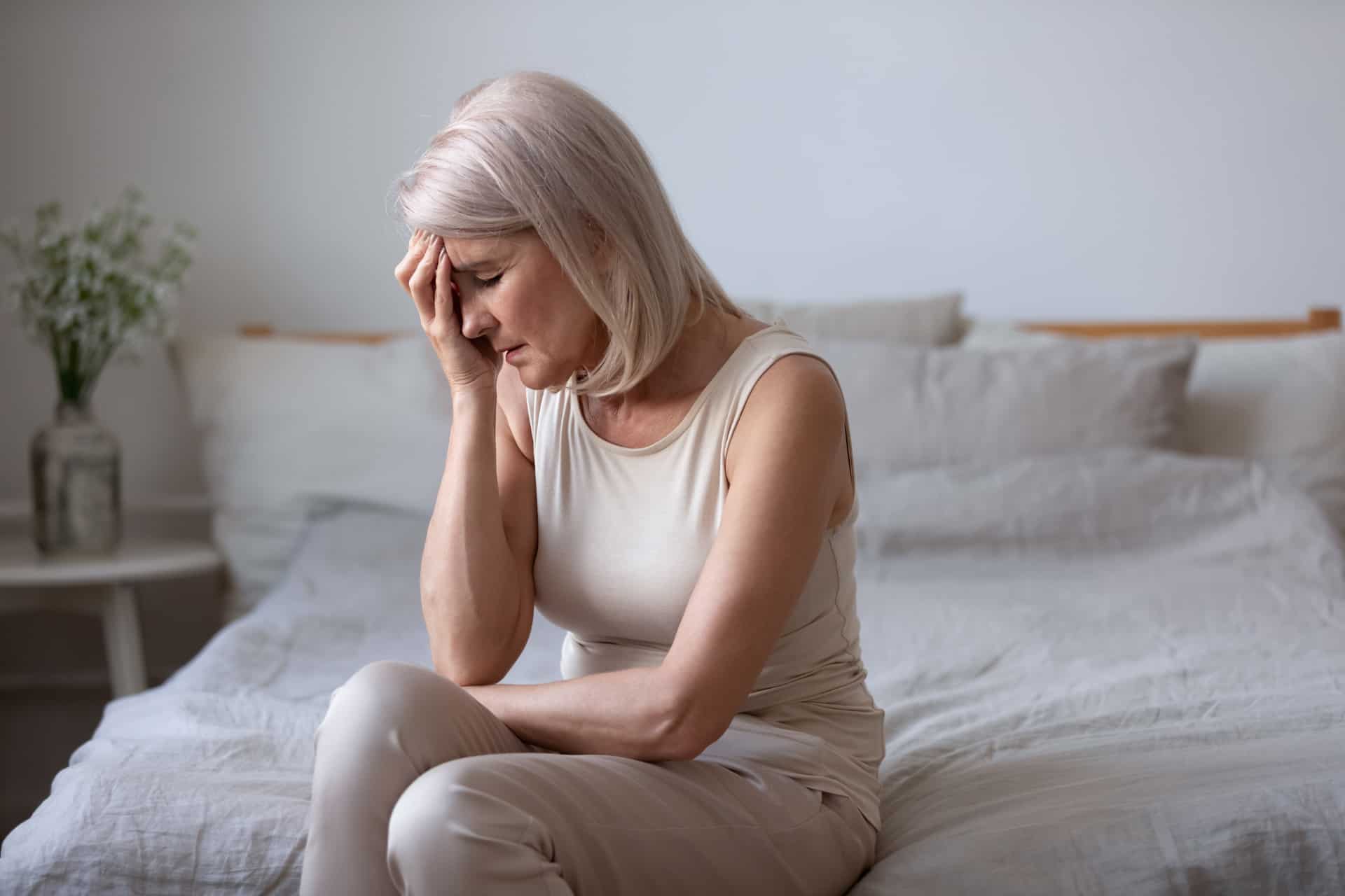  An old woman sitting on a bed looking exhausted