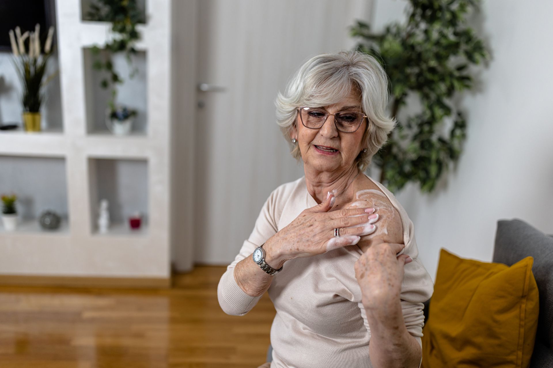 An older woman lathering BHRT cream on her shoulder