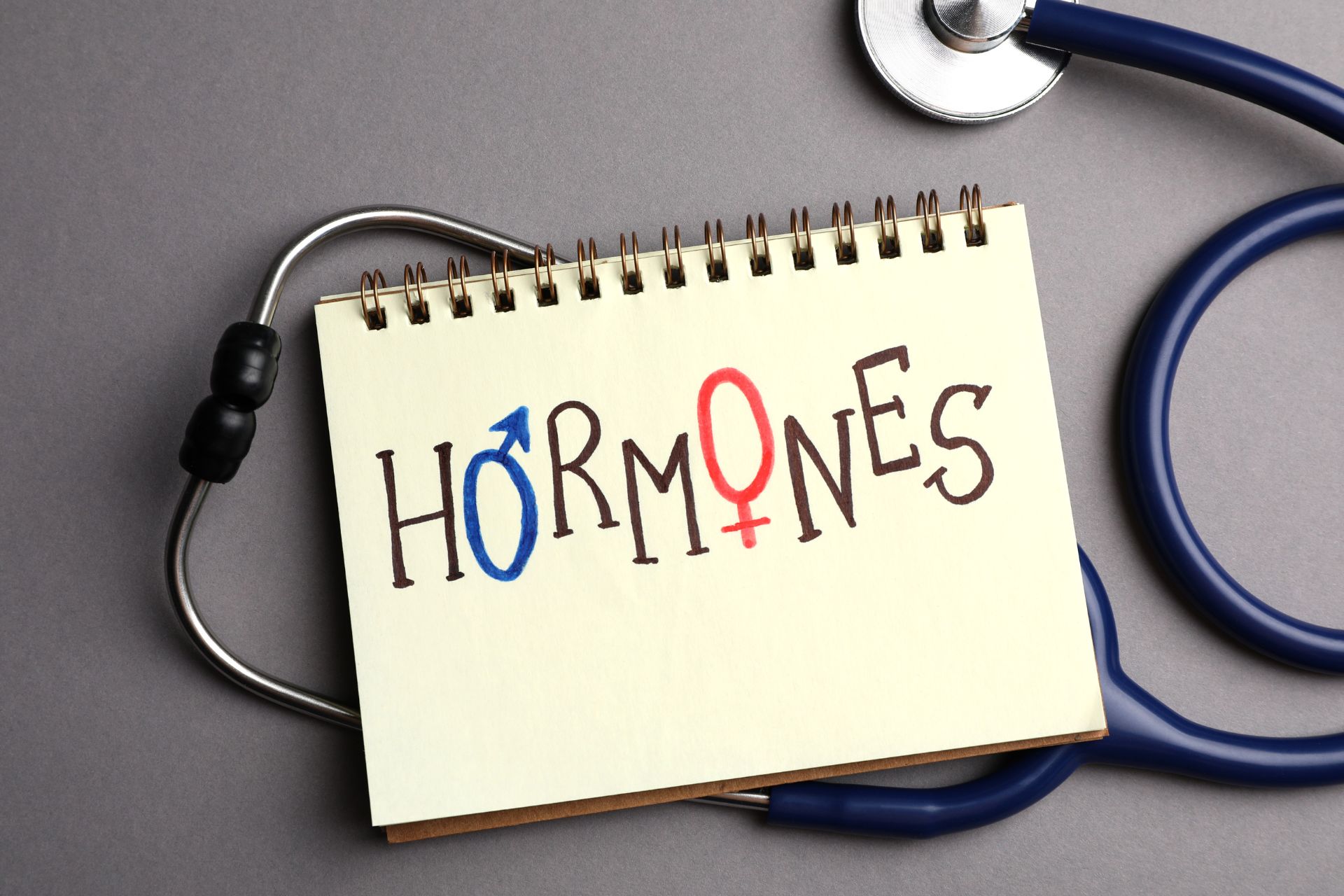 The word “Hormones” written on a notebook on top of a stethoscope