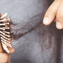 A woman pulling out clumps of hair from her hairbrush